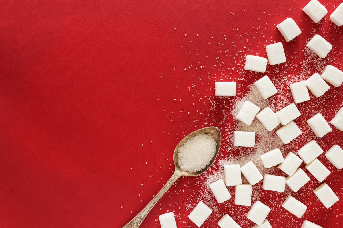 Ein Zuckerlöffel und Würfelzucker auf rotem Hintergrund